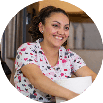 a smiling woman holding cleaning supplies